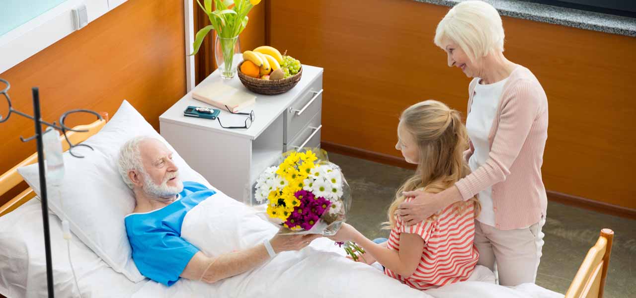 Ein Mann wird im Krankenhaus von Angehörigen besucht. Er bekommt Blumen.