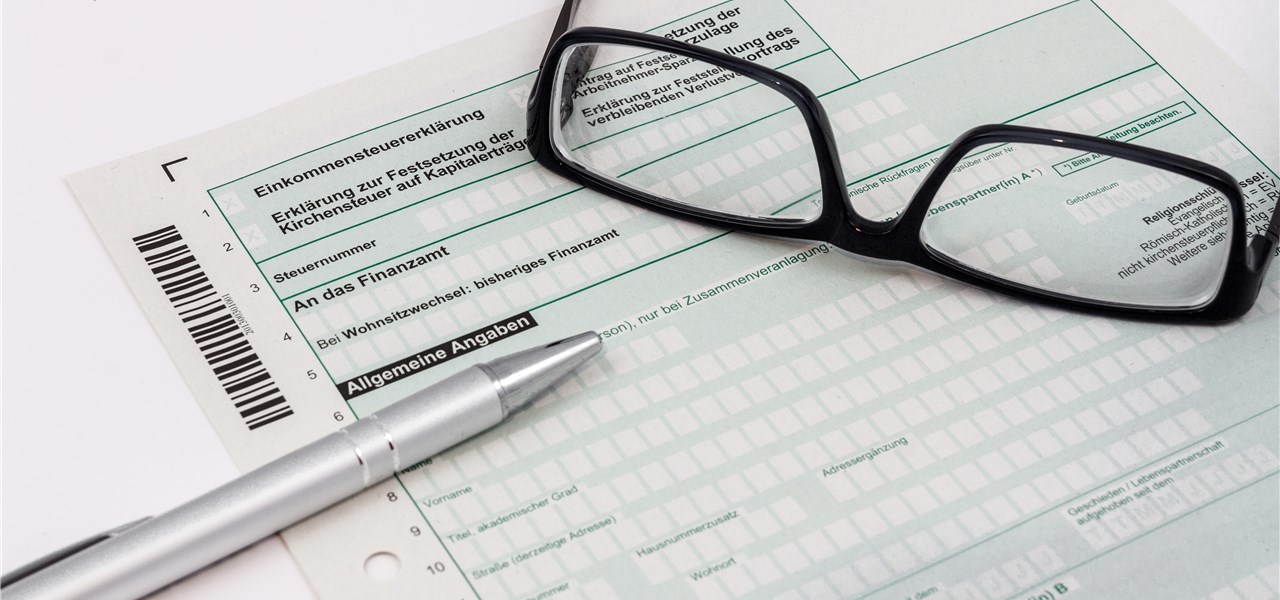 Auf einem Formular für die Steuererklärung liegen ein Kugelschreiber und eine Brille.