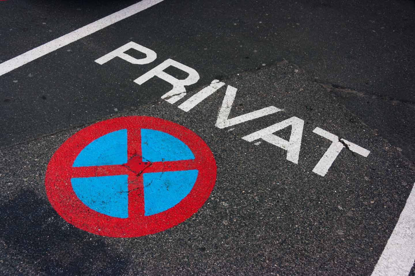 Privatparkplatz mit aufgesprühtem Halteverbots-Symbol auf dem Boden.