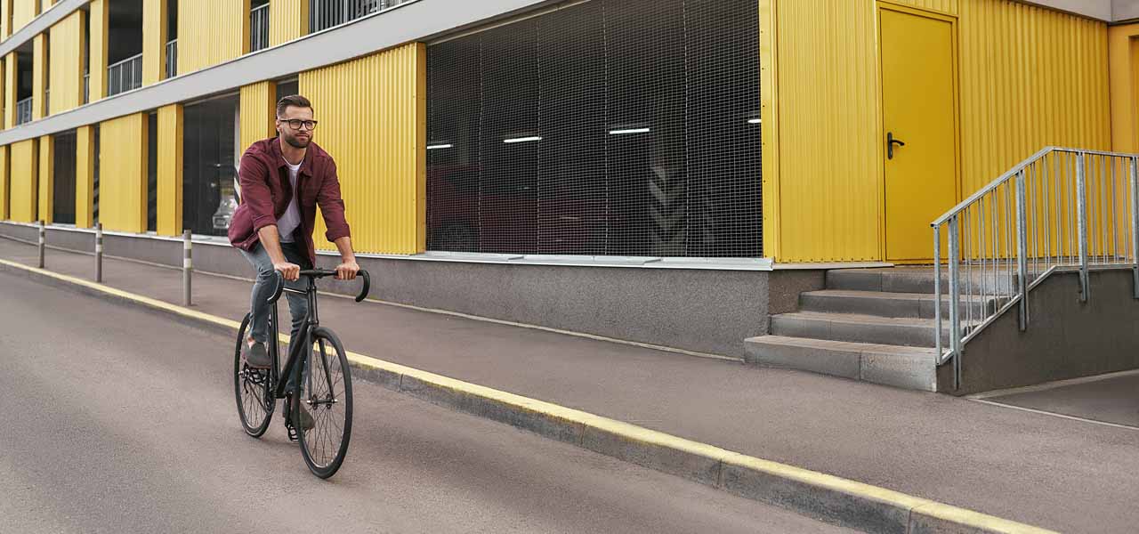 Ein Mann auf einem Rennrad fährt an einem gelben Gebäude vorbei.