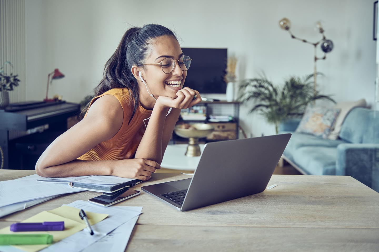 Junge Frau mit Headset sitzt lachend an ihrem Laptop.