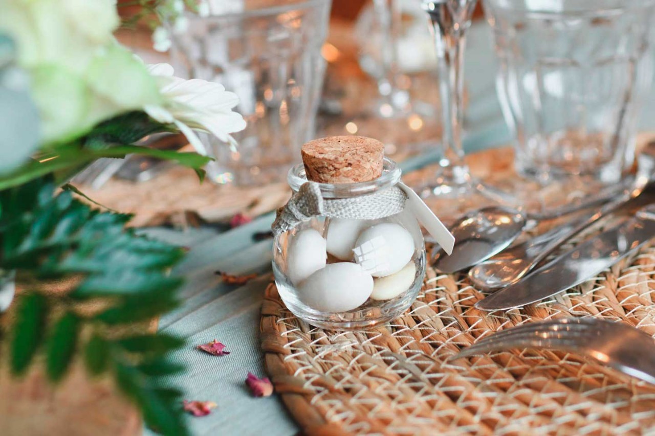 Kleines Gläschen mit Hochzeitsmandeln auf dem gedeckten Tisch.