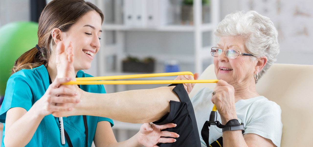 Frau trainiert ihr Bein mit Hilfe eines Bandes