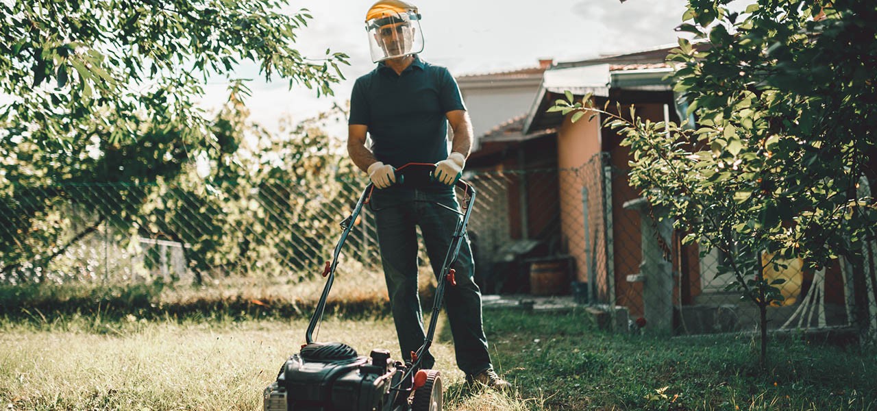 Sicherheit im Garten: Gärtner trägt Schutzausrüstung beim Rasenmähen